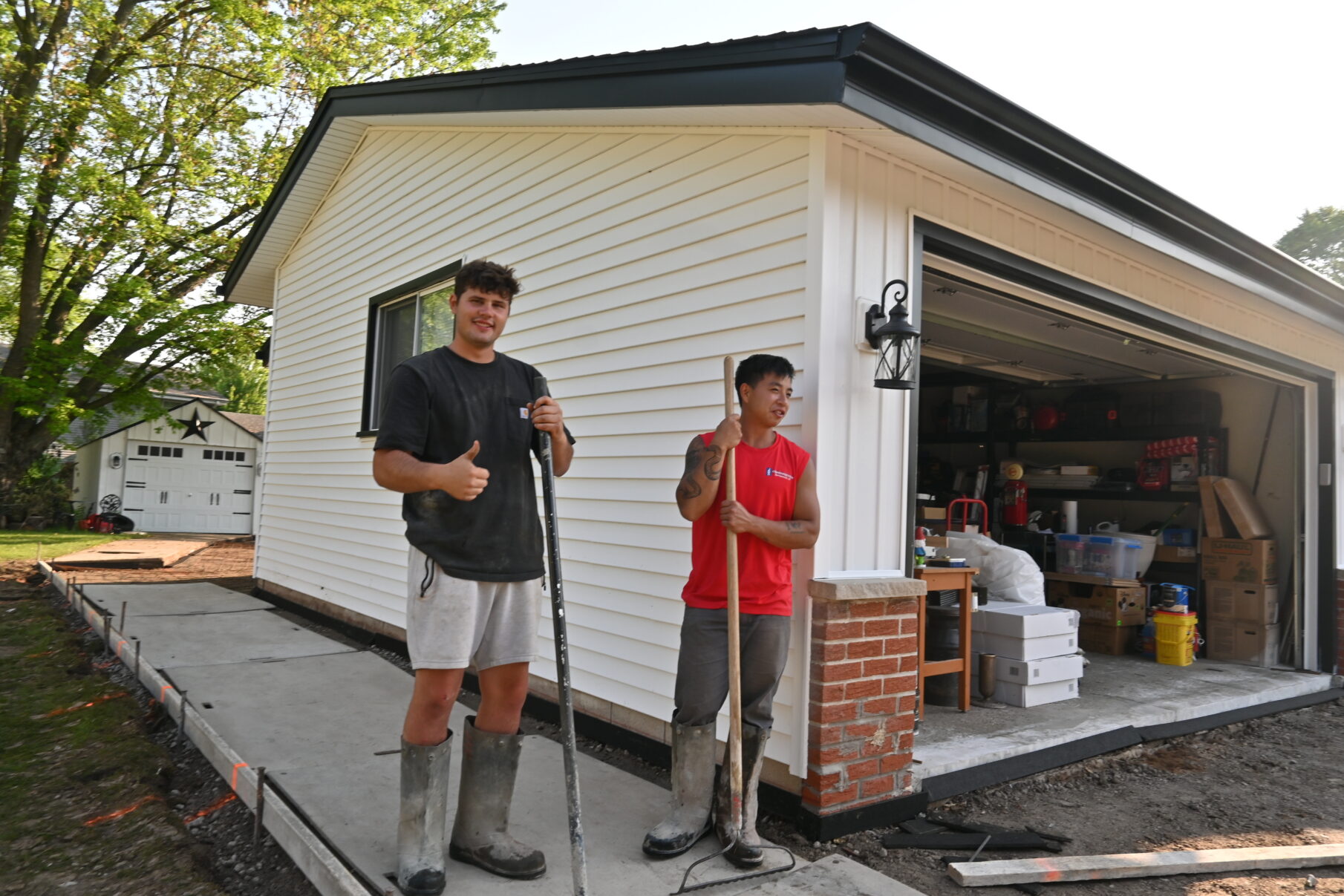 Two JBS crew members beside a newly poured concrete walkway and garage