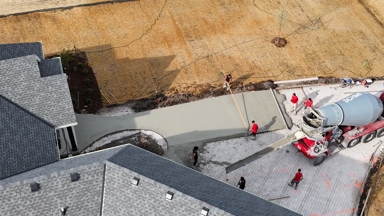 Aerial view showing the prepared driveway layout and the JBS crew placing and finishing concrete
