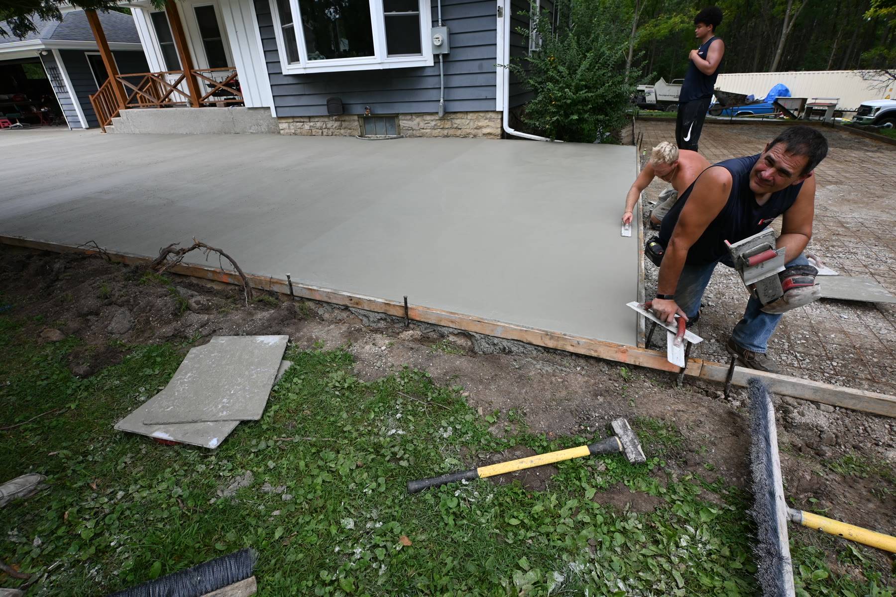 Jeff Stephan finishing the edge of a concrete patio alongside the crew